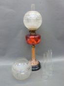 An oil lamp with cranberry bowl, reeded brass column,