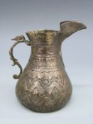 A Middle Eastern or similar white metal jug with embossed decoration, height 9.