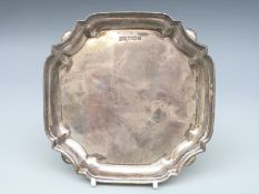 A Walker & Hall George V hallmarked silver salver with shaped edge, raise on four squat ball feet,