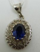 An 18ct white gold pendant set with an oval sapphire surrounded by paste