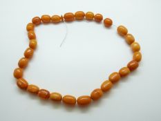 A Baltic amber necklace of 28 oval beads the largest approximately 1.6 x 1.