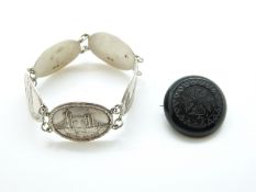 A silver bracelet made up of plaques depicting tourist areas in London and a jet brooch