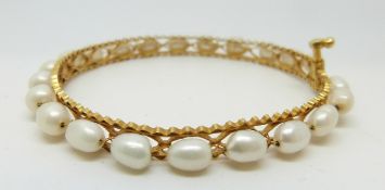 A yellow metal bangle set with pearls, 10.