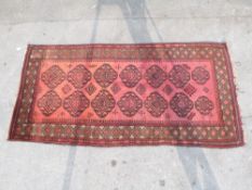 An Afghan rug with central pattern of fourteen large guls on a red ground,