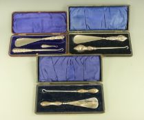 Three cased hallmarked silver handled button hook / shoe horn sets, Birmingham 1900,