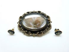 A Victorian brooch set with black enamel, the glass compartment to the centre set with hair,