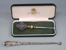 A cased hallmarked silver millennium button hook and a white metal handled button hook marked