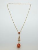 A 15ct gold necklace with a drop pendant set with two rose coral carvings
