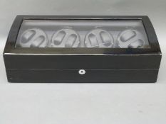 A quad electric wristwatch winder with capacity to wind eight watches and storage for a further