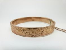 A 9ct rose gold bangle with chased foliate design, 11.