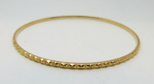 A yellow metal bangle with textured design, 9.