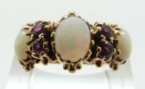 A Victorian ring set with three opal oval cabochons and four round cut rubies with foliate design