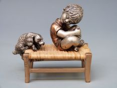 A novelty white metal or similar and bronzed model of a boy and a dog on a rush seated stool,