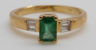 An 18ct gold ring set with an emerald cut emerald of approximately 0.