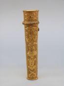 An 18thC gilt metal bodkin case with relief decoration of a jester or acrobat on a pedestal,