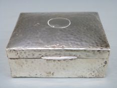 A George V hallmarked silver cigarette case with Arts & Crafts style hammered decoration,