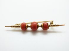 An 18ct gold brooch set with three coral beads,