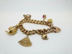 A 9ct gold curb link bracelet with five 9ct gold charms and two heart padlocks, 26.