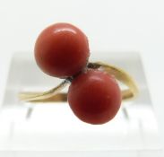 A yellow metal ring set with two coral cabochons, size N/O,