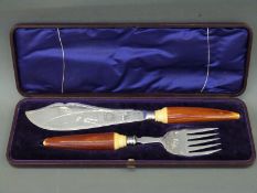 A cased set of silver plated fish servers with engraved decoration and stained ivory handles