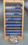 A glass fronted wooden display case with approximately 55 spoons,