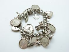 A silver charm bracelet with coin charms, silver heart, dog, cow,