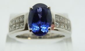 An 18ct white gold ring set with tanzanite and princess cut diamonds to the shoulders, size P, 9.