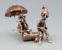 A novelty part white metal figure group of two bearded men, one with umbrella the other a pipe,