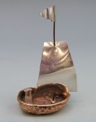 A novelty miniature boat, the hull formed as a walnut shell with white metal sail, height 73mm,