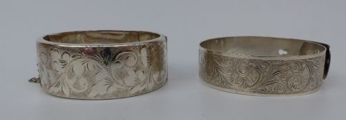 A hallmarked silver bangle with chased foliate design and a silver bangle with scrolling design,