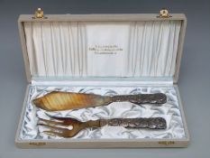 A cased pair of Swedish white metal fish servers with 813H Swedish silver marks for 1907,