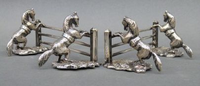 A pair of novelty silver plated knife rests in the form of horses before fences, length 10.