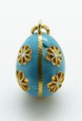 An 18ct gold enamel egg pendant decorated with flowers on a blue enamel ground,