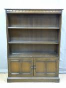 A stained elm bookcase with adjustable shelves and cupboard below,