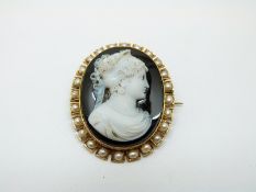 A Victorian brooch set with a hardstone cameo depicting a woman,