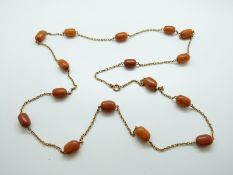 A Victorian yellow metal necklace set with barrel-shaped amber beads, the largest approximately 1.