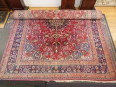 A Persian red ground rug with central motif and blue border,