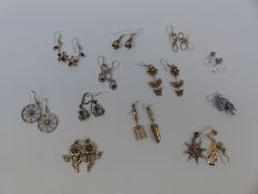 A quantity of silver earrings, some depicting flowers, one pair a gardening trowel and fork,