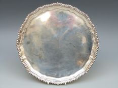 A hallmarked silver salver with rope twist rim, raised on three scroll feet,