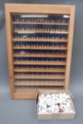 A glass fronted wooden display case with approximately 190 thimbles,