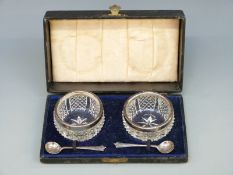 A boxed cut glass cruet with silver rims and spoons