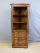 A reproduction oak corner cupboard with display shelves and lower cupboard,