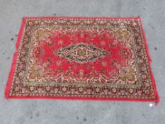 A red ground Persian wool rug with central motif,