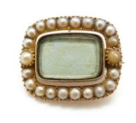 A Victorian mourning brooch set with a border of pearls and a glass compartment to the centre