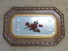 An Edwardian oak framed bevelled glass mirror with hand painted rose decoration,