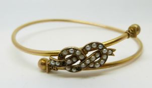 A late Victorian bangle set with seed pearls with sphere ends, marked 9ct,