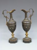 A pair of 19thC bronze pedestal ewers with gilt and foliate decoration raised on beaded bases,