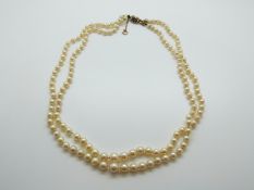 A two strand cultured pearl necklace with 9ct gold clasp set with an amethyst and pearls