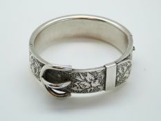 A white metal Victorian bangle with engraved foliate and buckle design