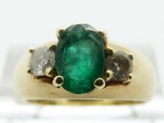 A 14ct gold ring set with an oval emerald and two diamonds, size M, 6.